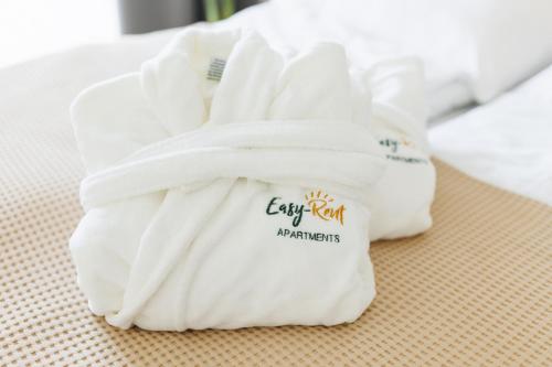 stos białych ręczników siedzących na łóżku w obiekcie Prestige House Apartament - 2 sypialnie z ogródkiem i basenem w Pobierowie
