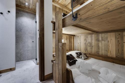 1 dormitorio con 1 cama grande en una habitación con paredes de madera en Résidence La Charpenterie - Pièces 284, en La Rosière