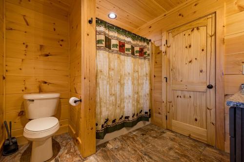 a log cabin bathroom with a toilet and a shower at Sweet Mountain Memories Relax affordably cozy cabin with hot tub, game room, and mountain views! in Cosby