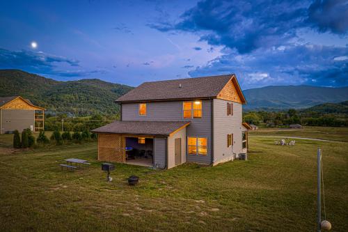 a house in a field with mountains in the background at Sweet Mountain Memories Relax affordably cozy cabin with hot tub, game room, and mountain views! in Cosby