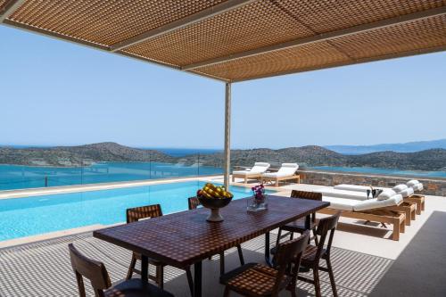 a patio with a table and chairs and a pool at Elounda Bright Villa in Elounda