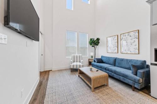 a living room with a blue couch and a tv at Cypress House*Cozy, Chic, and yours to book now! in Lafayette