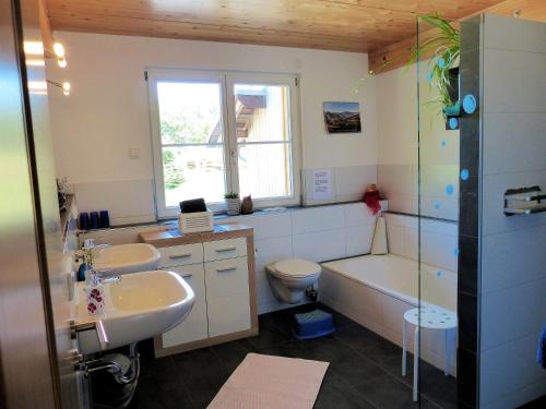 een badkamer met 2 wastafels, een bad en een toilet bij Sonnerhof Hofsgrund in Oberried