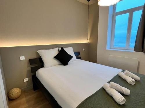 een slaapkamer met een groot wit bed met 2 kussens bij L’émeraude : vue mer - MALO’Cation in Duinkerke