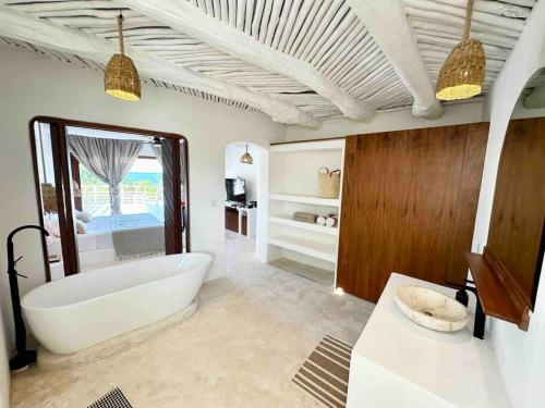 y baño con bañera blanca y lavamanos. en Unique Beachfront Casa Kyma, Pool, San Crisanto, Yucatan, en San Crisanto