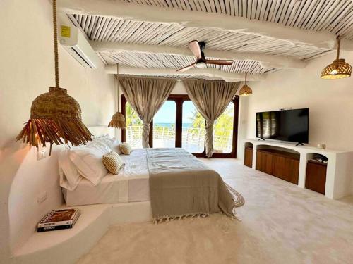 1 dormitorio con 1 cama grande y TV en Unique Beachfront Casa Kyma, Pool, San Crisanto, Yucatan, en San Crisanto