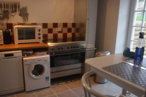a kitchen with a microwave and a stove and a table at Propriete d'une chambre avec terrasse et wifi a Colonard Coruberta in Courcerault