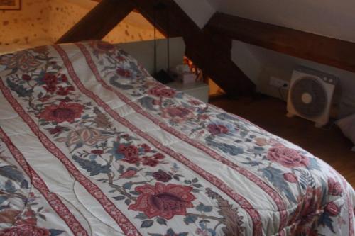 a bed with a floral comforter on top of it at Propriete d'une chambre avec terrasse et wifi a Colonard Coruberta in Courcerault
