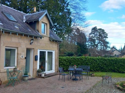 um pátio com uma mesa e cadeiras em frente a uma casa em Beautiful Historic Cottage em Callander