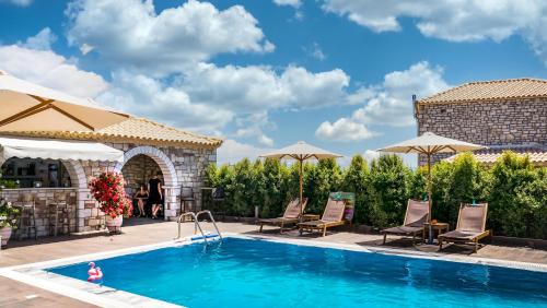 a pool with chairs and umbrellas on a patio at LIOKRINA country living villas & suites in Koroni