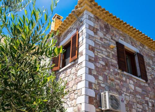 a brick building with windows and a tree at LIOKRINA country living villas & suites in Koroni