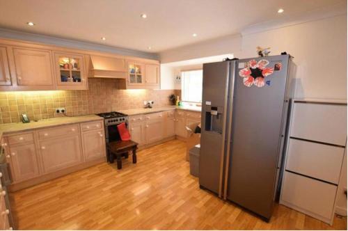 a kitchen with a stainless steel refrigerator and wooden floors at 8 Warren close Stanford-Le-Hope in Stanford-le-Hope