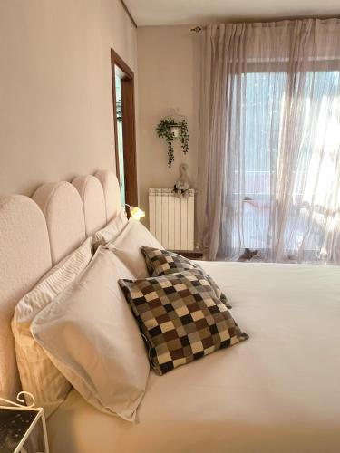 a large white bed with a checkered pillow on it at Il Giardino di Cristina - A literary B&B in Chianti in Vagliagli