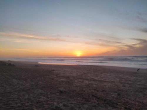 a sunset on a beach with the ocean at Gaal-Gui, chez Guillaume in Mboro
