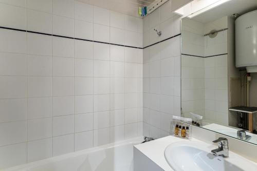 Baño blanco con lavabo y bañera en Résidence La Reine Blanche - Studio pour 4 Personnes 244, en Val Thorens