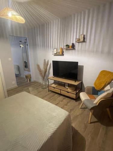 - une chambre avec un lit, une télévision et une chaise dans l'établissement Le petit sanvignard, à Sanvignes-les-Mines