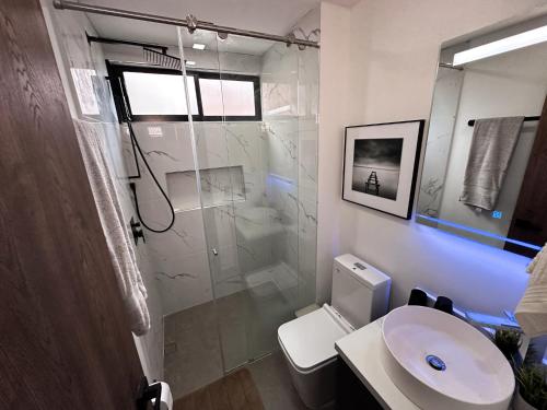 uma casa de banho com um chuveiro, um WC e um lavatório. em Luxe Apt in Laureles by Hoost em Medellín