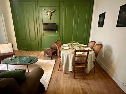 een eetkamer met een tafel en een groene deur bij Le Sauvage - 7 personnes - Gare - BCLA in Le Mans