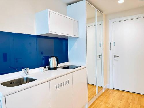 - une cuisine blanche avec des murs bleus et un évier dans l'établissement Orbi City Apartment Sea View, à Batoumi