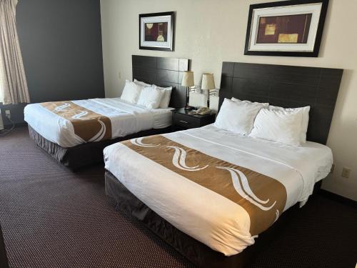 Quality Inn & Suites Hattiesburg في هاتييسبورغ: سريرين في غرفة فندق بسريرين