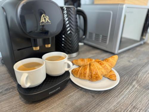 twee kopjes koffie en een bord croissants bij Elegant One Bedroom Apartment in Swindon
