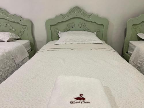 a green and white bed with a white blanket on it at Hotel Cisne in Cuenca