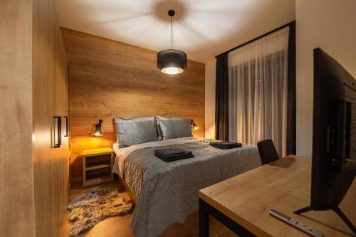 デマノブスカ・ドリーナにあるApartmán naCHALETY JASNÁのベッドと机とテレビのある寝室