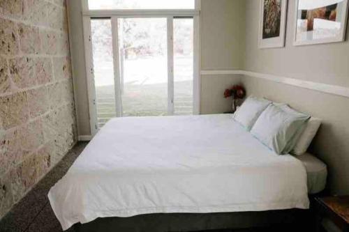 a bedroom with a large white bed with a window at Glenberrie Place ECO Retreat in Kangarilla