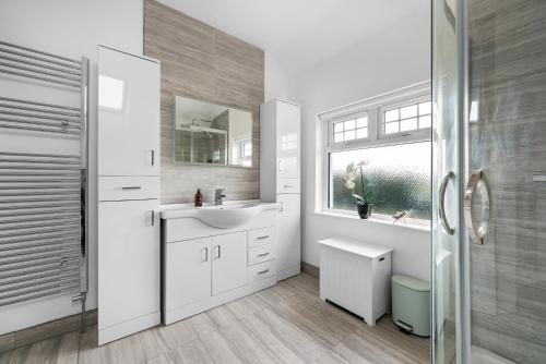 a white bathroom with a sink and a shower at LONG TERM STAY SPECIAL OFFER AVAILABLE! 5-Bedroom Spacious, Stunning Design, Sociable Areas & Cosy House Near South Downs Park, Sleeps 11 with GAMES Room, PRIVATE PARKING and GARDEN - by Blue Puffin Stays in Waterlooville