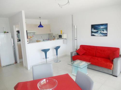 un salon avec un canapé rouge et une cuisine dans l'établissement Bel appartement face mer 100m plages, à Cavalaire-sur-Mer