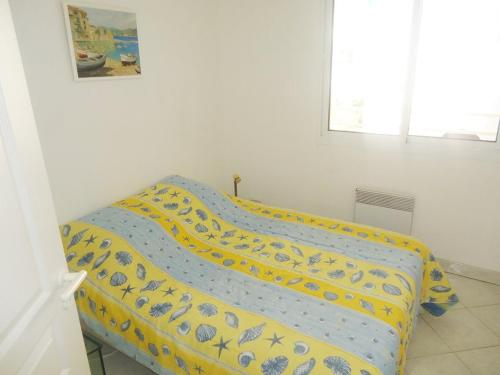 - un lit avec une couette jaune et bleue dans l'établissement Bel appartement face mer 100m plages, à Cavalaire-sur-Mer