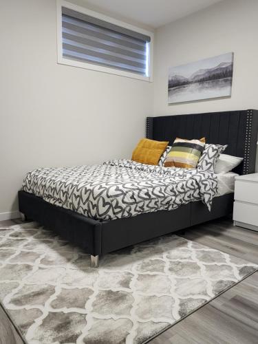 a bedroom with a bed with a black headboard and a rug at Trendy 2-Bed Oasis Awaits! in Calgary