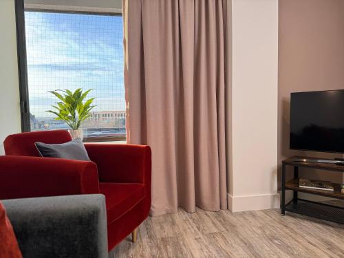 een woonkamer met een rode stoel en een televisie bij Elegant One Bedroom Apartment in Swindon