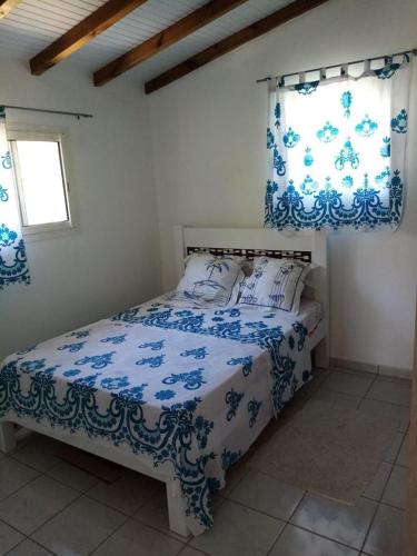 a bedroom with a bed with blue and white sheets at Villa des fleurs in Pointe-Noire