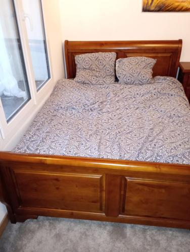 uma cama com uma estrutura de madeira e almofadas em La Forge em Santilly