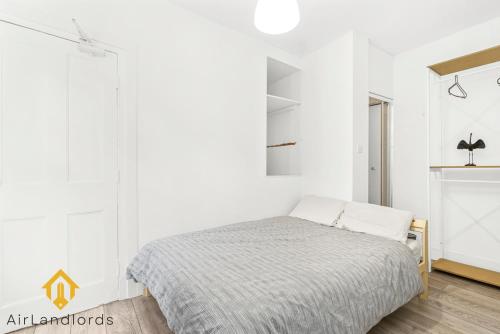 1 dormitorio con 1 cama y paredes blancas en Fab 3bed 3bath Flat Kings Cross, en Londres