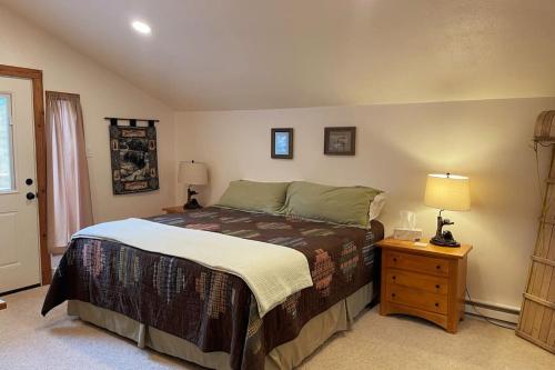 a bedroom with a bed and a night stand with a lamp at Shady Pines- Cozy Mountain Retreat in Idaho Springs