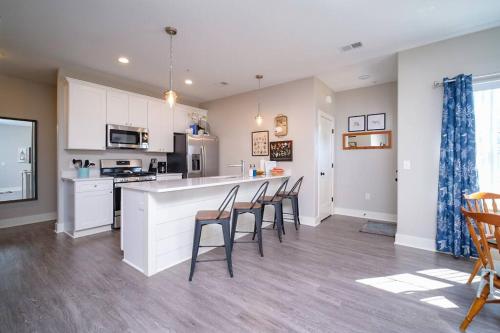 a kitchen with white cabinets and a bar with chairs at Main Floor Cozy 2 Bedroom Condo in Bettendorf in Bettendorf
