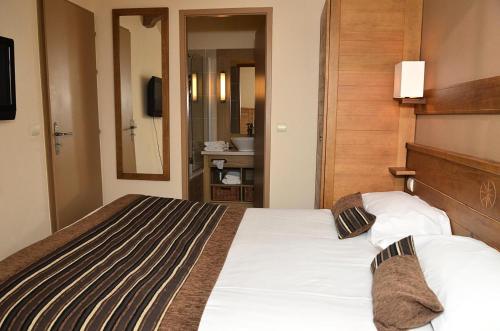 a hotel room with a bed and a mirror at Résidence Les Terrasses D'eos - Appartement confortable · Accès direct aux pistes · Piscine · Spa · WIFI gratuit et illimité MAE-6164 in Magland