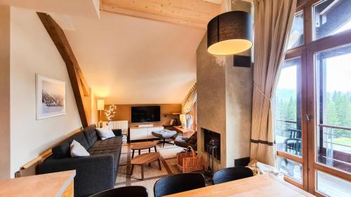 a living room with a couch and a fireplace at Résidence Les Terrasses D'eos - Appartement confortable · Accès direct aux pistes · Piscine · Spa · WIFI gratuit et illimité MAE-6164 in Magland