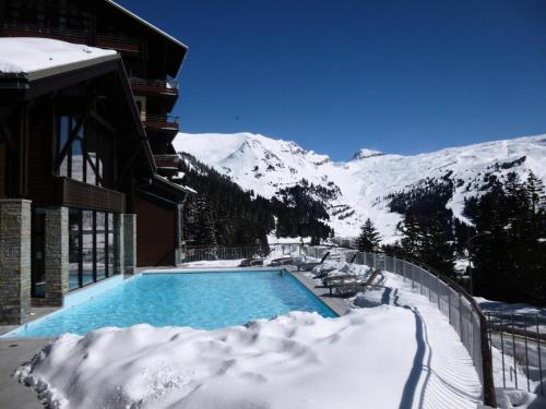 a swimming pool covered in snow next to a building at Résidence Les Terrasses D'eos - Appartement confortable · Accès direct aux pistes · Piscine · Spa · WIFI gratuit et illimité MAE-6164 in Magland