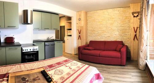 un salon avec un canapé rouge dans une cuisine dans l'établissement Résidence Zodiaque - BEAU 2 PIECES CABINE MAE-0874, à Villarembert