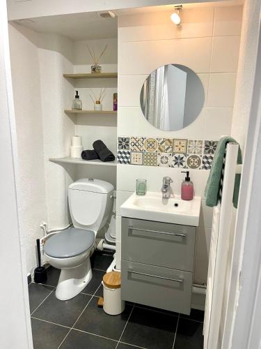 a bathroom with a toilet and a sink and a mirror at L’émeraude - T2 en plein coeur de Dinan in Dinan
