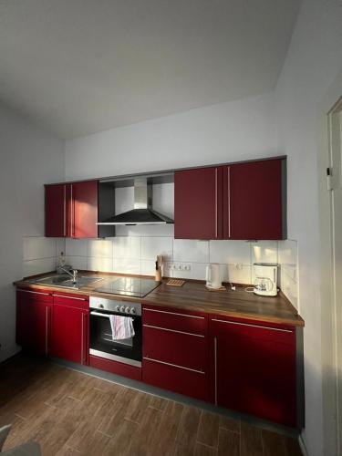 a kitchen with red cabinets and a stove at Suite One - Haus Varel in Varel