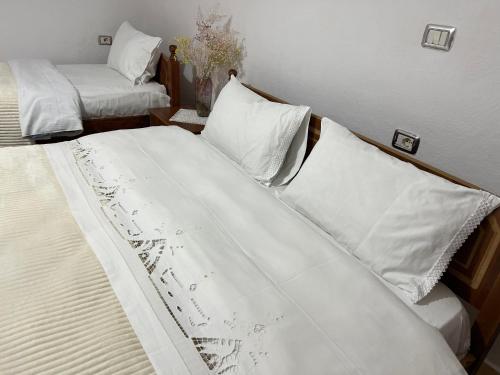 1 dormitorio con 2 camas con sábanas y almohadas blancas en Tourists Guest House, en Gjirokastra
