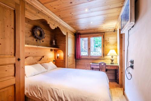 ein Schlafzimmer mit einem Bett in einem Holzzimmer in der Unterkunft Chalet As De Coeur - Chalets pour 14 Personnes 224 in Morzine