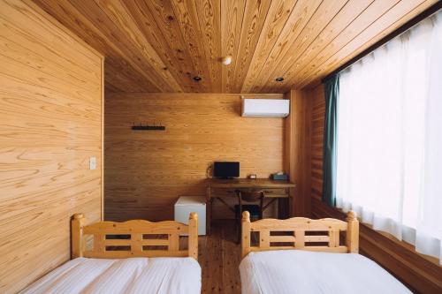 two beds in a room with wooden walls and a window at Noasobi lodge - Vacation STAY 80823v in Arao