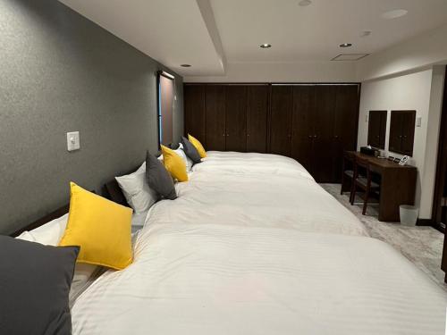 ein großes weißes Bett mit gelben Kissen in einem Zimmer in der Unterkunft LIT'S INN Sapporo - Vacation STAY 47714v in Sapporo