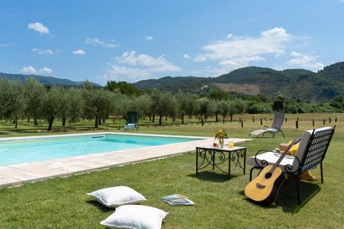 une guitare assise sur une pelouse à côté d'une piscine dans l'établissement Giardino di Tosca, à Morro
