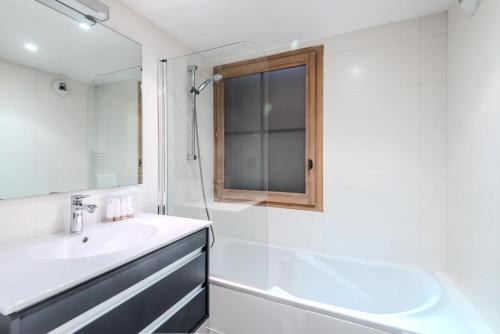 ein weißes Badezimmer mit einem Waschbecken und einem Spiegel in der Unterkunft Résidence Les Balcons Des Bois Venants Bat A - Pièces 444 in Morzine